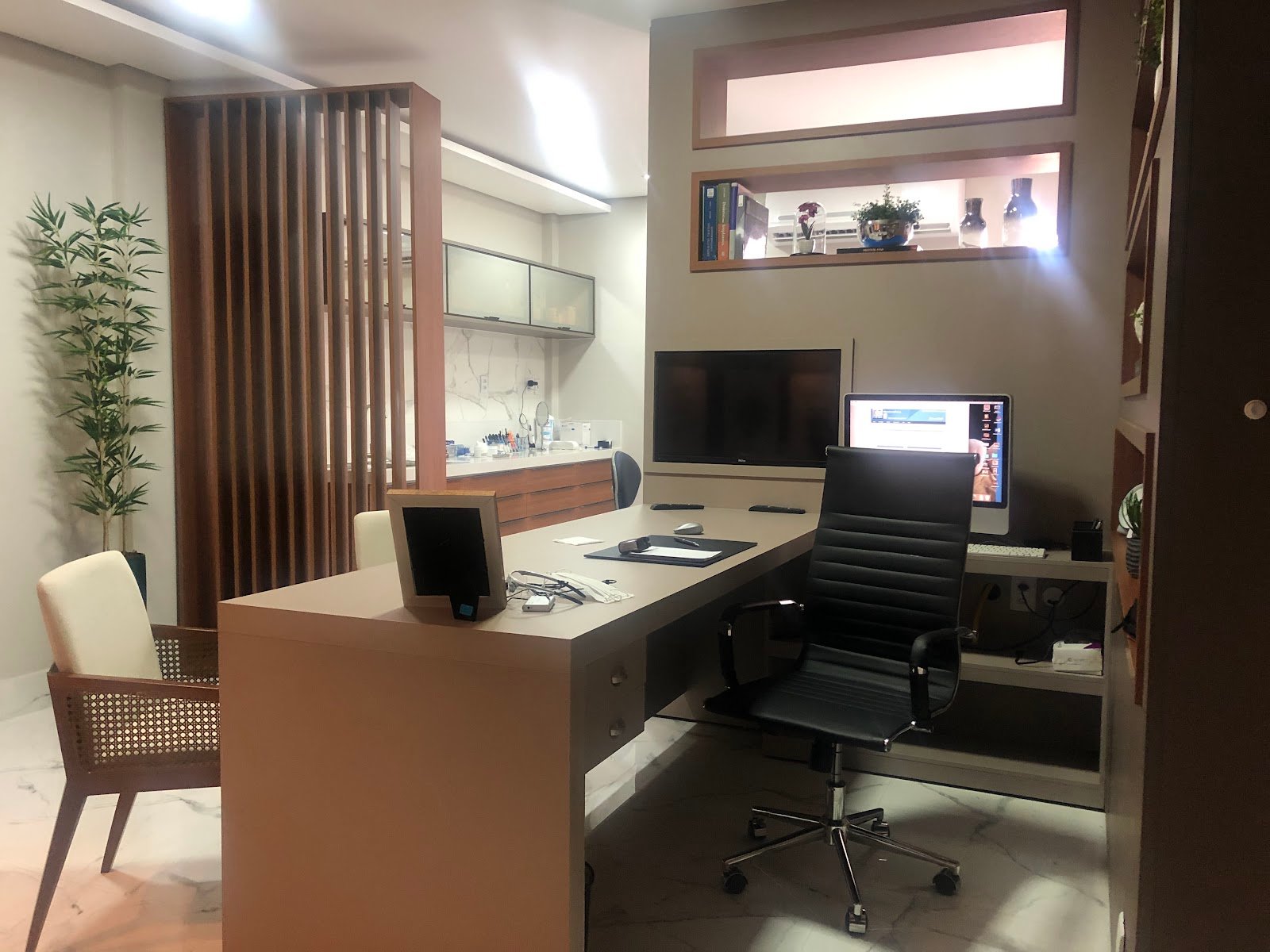 Consultório do Dr. Erasmo Correa com mobiliário em madeira, poltrona de atendimento e piso de mármore.